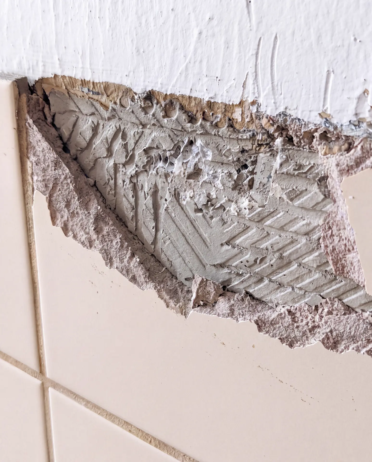 Beschädigte Wand mit freigelegtem Putz und Fugenmörtel – typischer Asbestverdacht in Bauten vor 1990