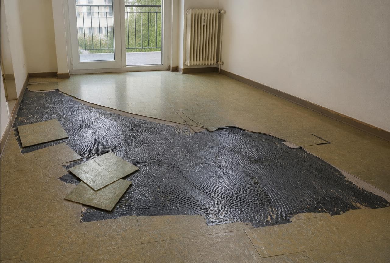 Angehobene Vinylplatten in einer Schweizer Wohnung mit schwarzem Bitumenkleber auf dem Unterlagsboden