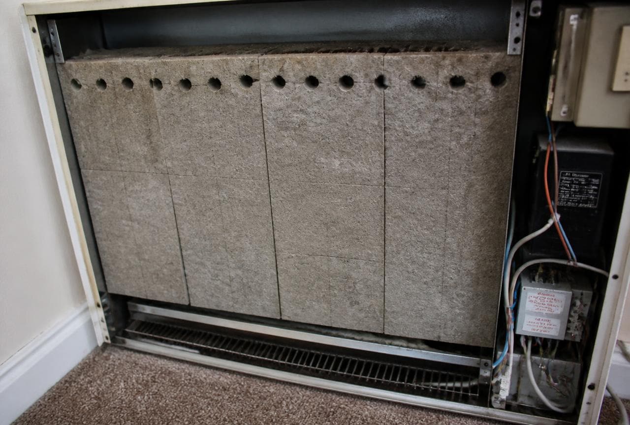 Geöffneter Elektro-Nachtspeicherofen mit grauen, faserigen Dämmplatten im Inneren